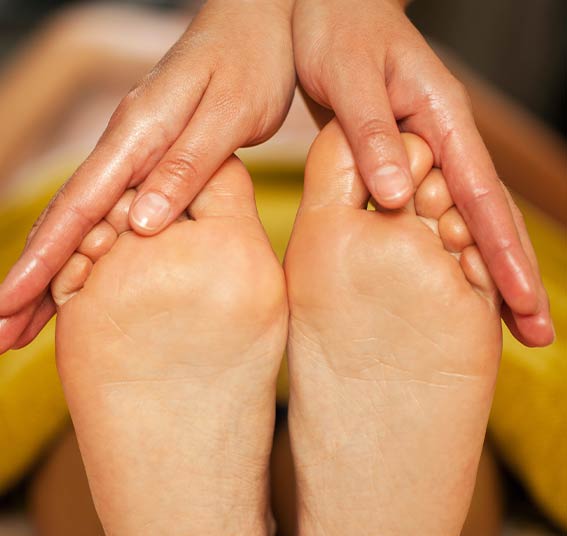 Réflexologue qui masse les pieds d'une cliente