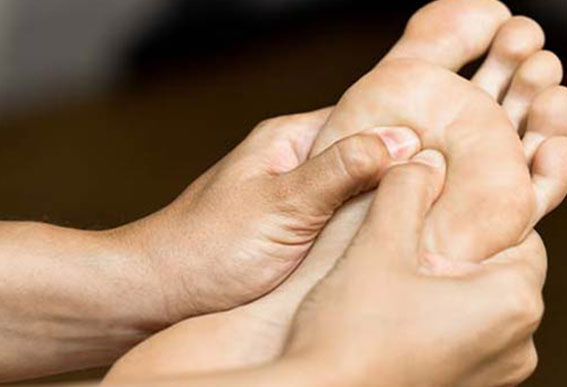 Réflexologue qui masse les pieds d'une cliente