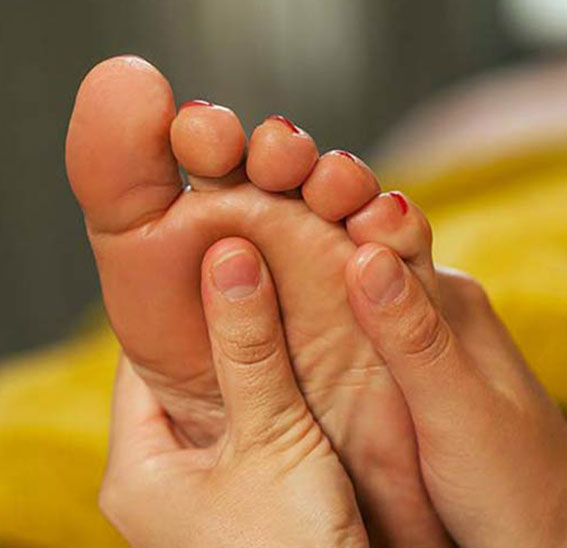 Réflexologue qui masse les pieds d'une cliente