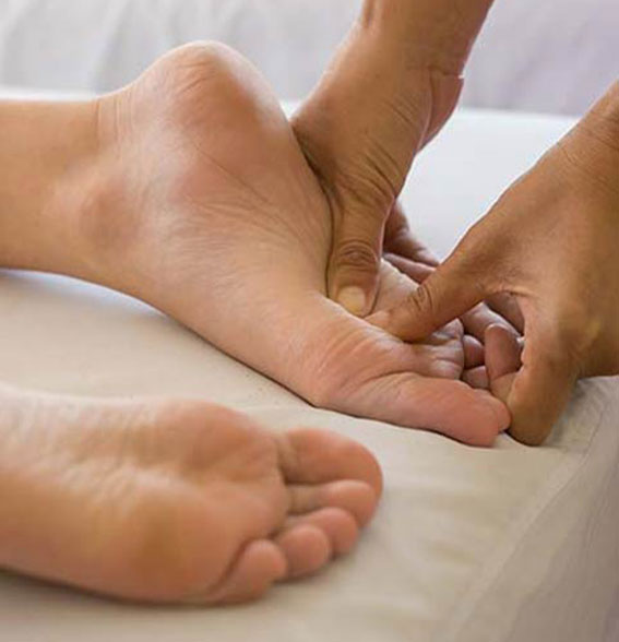 Réflexologue qui masse les pieds d'une cliente