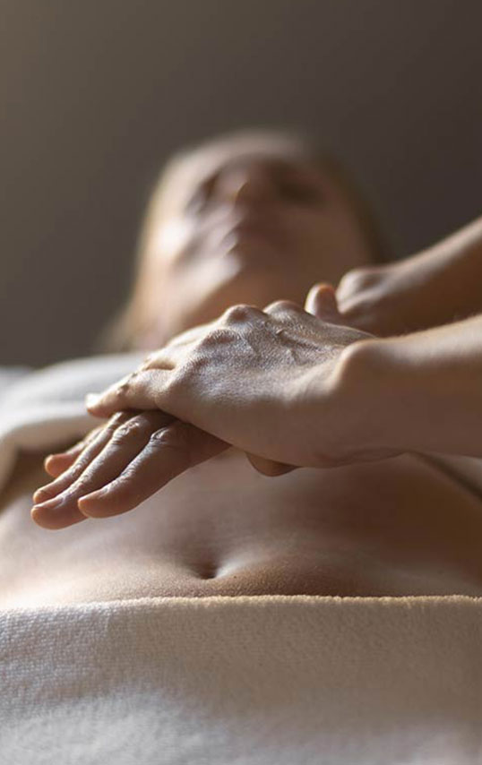 Masseuse qui fait un massage énergétique sur une cliente à domicile