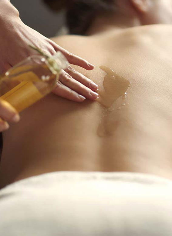 Masseuse qui fait un massage Ayurvédique Abhyanga à l'huile à une cliente