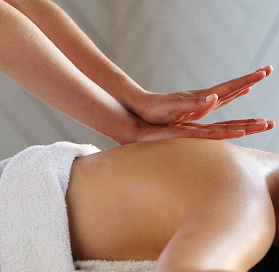 Masseuse qui fait un massage énergétique sur une cliente à domicile