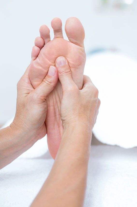 Réflexologue qui masse les pieds d'une cliente